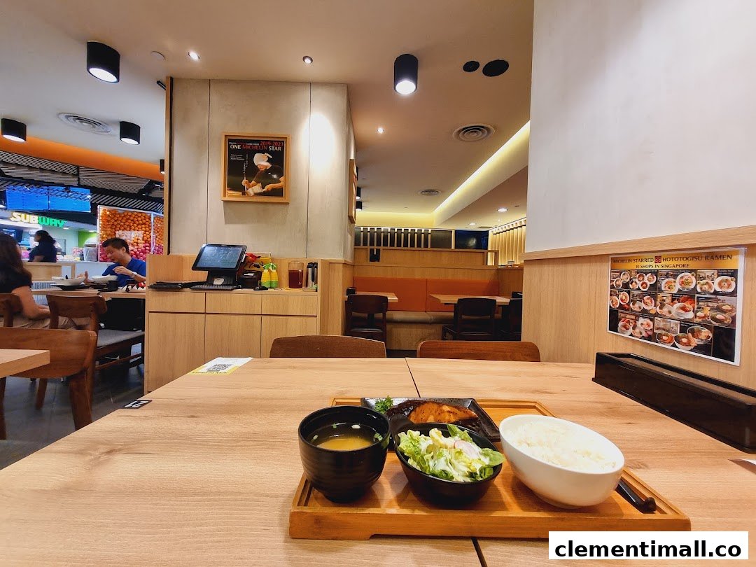 A delicious meal set on a wooden table inside Hototogisu Ramen, with the restaurant interior and mall visible.