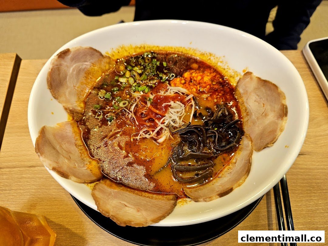 A vibrant bowl of ramen with rich broth, sliced pork, and various toppings on a wooden table.