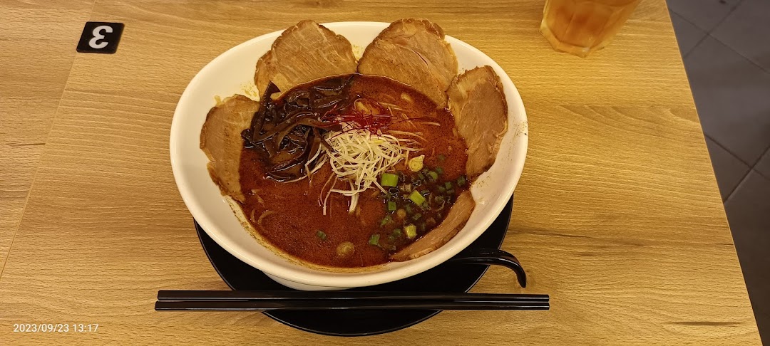 A vibrant bowl of ramen with rich broth, chashu, and fresh toppings on a wooden table.