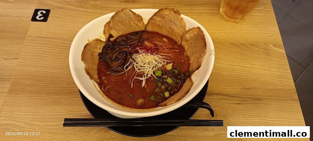 A vibrant bowl of ramen with rich broth, chashu, and fresh toppings on a wooden table.