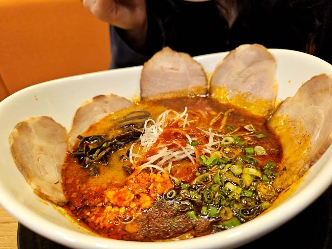A close-up of a vibrant bowl of ramen with rich broth, chashu, and various toppings.
