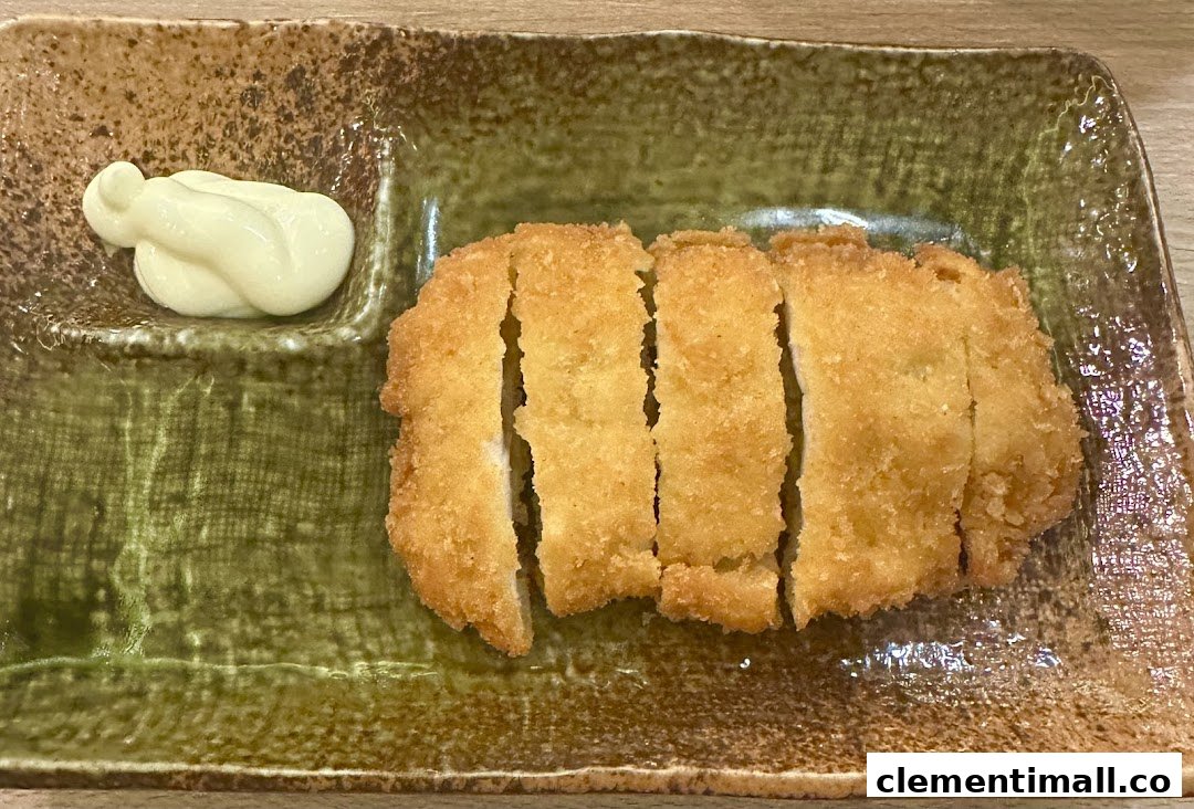 A golden-brown fried cutlet, sliced and served with a dollop of mayonnaise on a rustic plate.