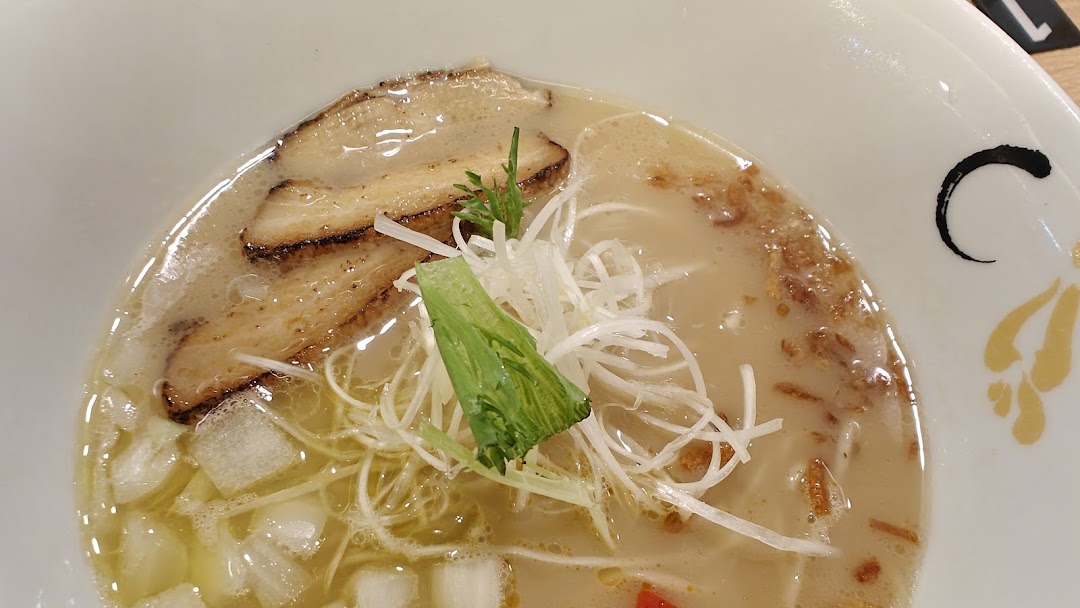 A close-up of a delicious bowl of ramen with pork slices, green onions, and other toppings.