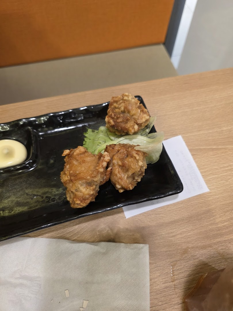 A close-up shot of crispy fried chicken (karaage) served with mayonnaise and lettuce on a black plate.