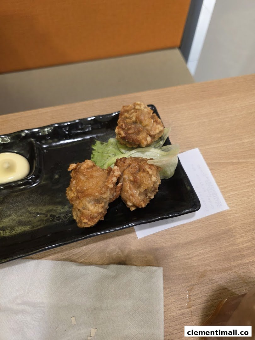 A close-up shot of crispy fried chicken (karaage) served with mayonnaise and lettuce on a black plate.