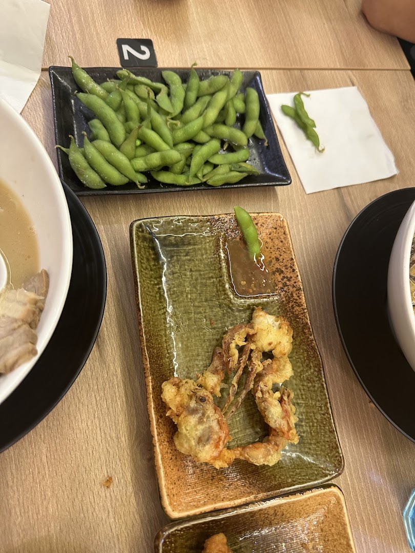 Close-up of delicious edamame and crispy soft-shell crab tempura served on a wooden table.