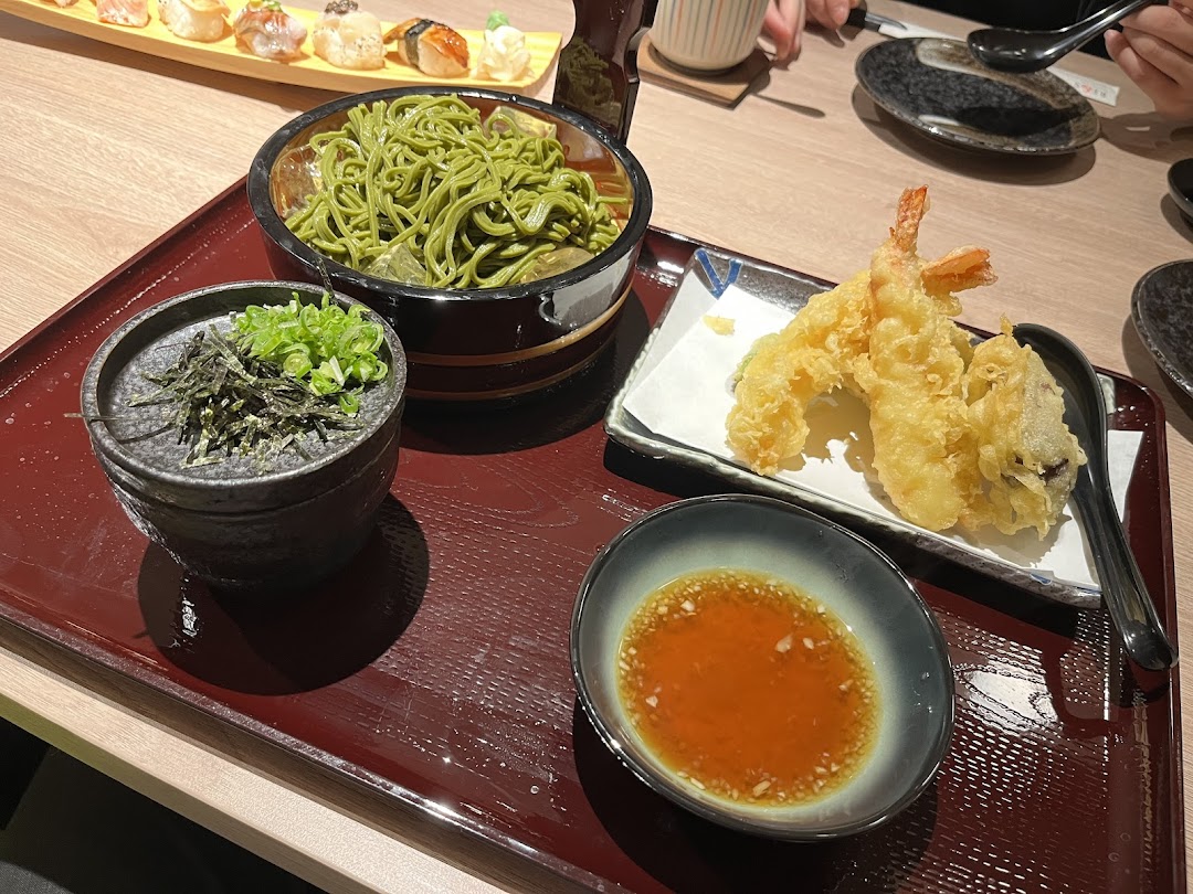 A delicious Japanese meal featuring green tea soba noodles, crispy tempura, and sushi on a tray.