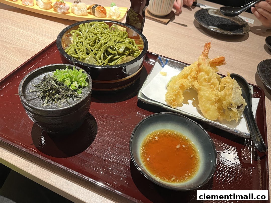 A delicious Japanese meal featuring green tea soba noodles, crispy tempura, and sushi on a tray.