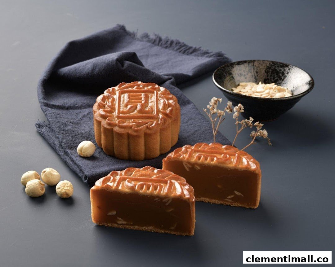 A whole and two sliced mooncakes with nuts and a bowl of almonds on a dark background.