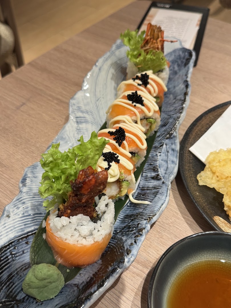 A beautifully presented plate of sushi rolls featuring salmon, shrimp, and roe, served with wasabi.