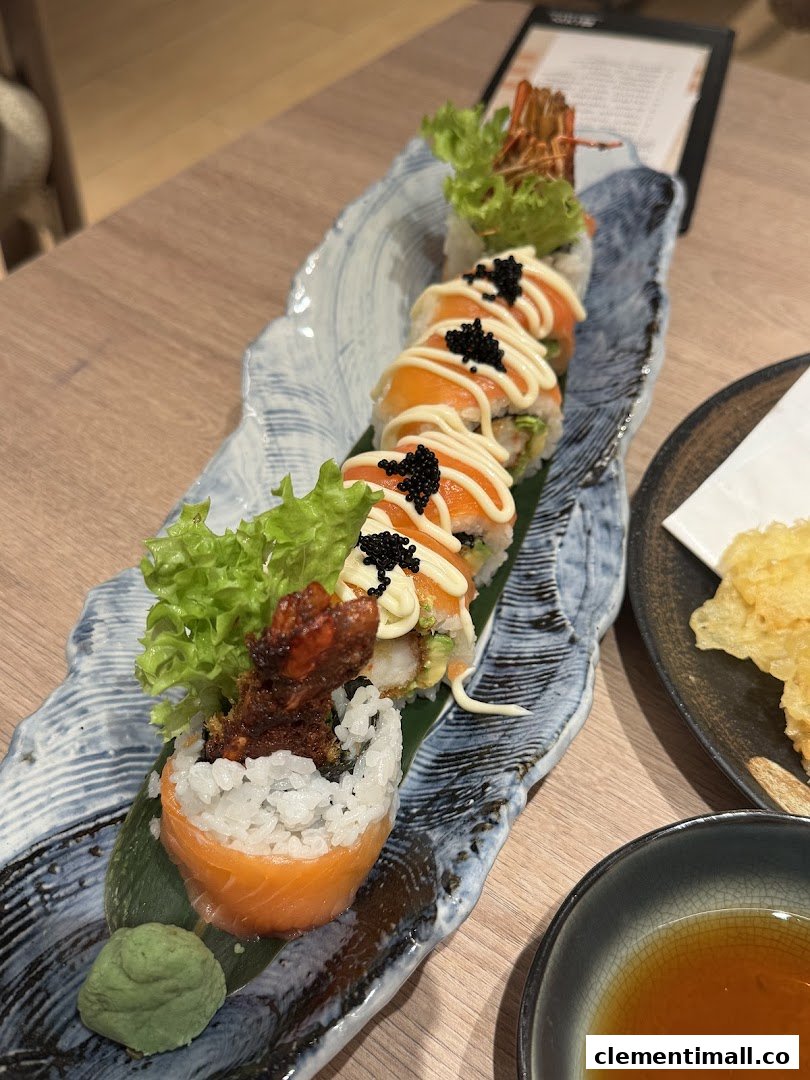 A beautifully presented plate of sushi rolls featuring salmon, shrimp, and roe, served with wasabi.