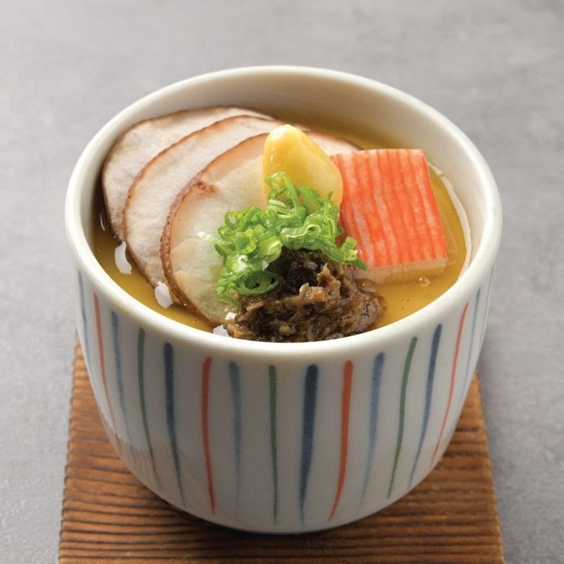 A beautifully presented Japanese chawanmushi (steamed egg custard) topped with sliced meat, crab stick, ginkgo nut, and spring onions.