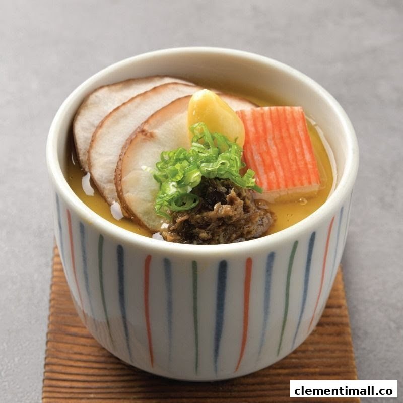 A beautifully presented Japanese chawanmushi (steamed egg custard) topped with sliced meat, crab stick, ginkgo nut, and spring onions.