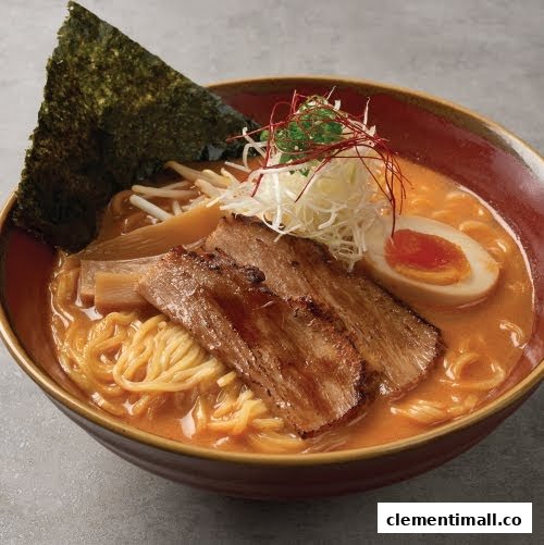 A vibrant bowl of ramen featuring chashu pork, a soft-boiled egg, seaweed, and fresh vegetables.