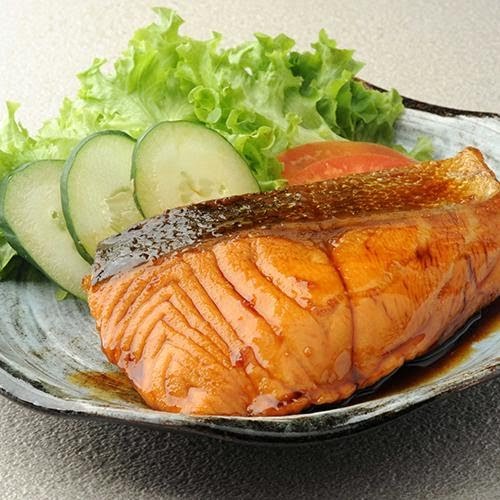 A close-up of a perfectly grilled salmon fillet with fresh lettuce and cucumber slices.