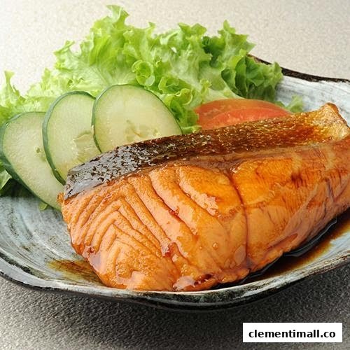 A close-up of a perfectly grilled salmon fillet with fresh lettuce and cucumber slices.