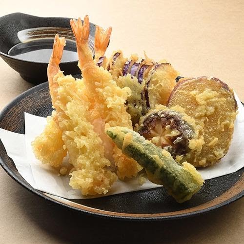 A close-up of a delicious plate of golden-fried tempura, featuring shrimp and assorted vegetables.