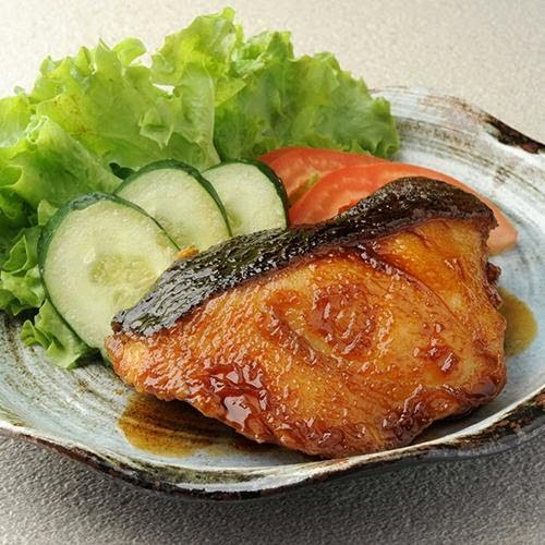 A close-up of a perfectly grilled fish fillet with crispy skin, served alongside fresh lettuce, cucumber, and tomato.