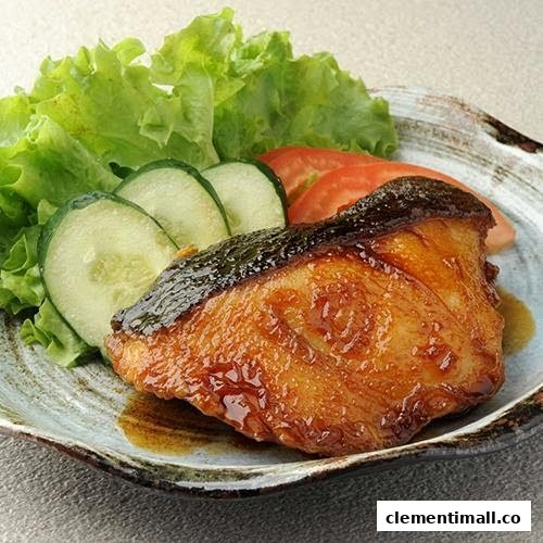 A close-up of a perfectly grilled fish fillet with crispy skin, served alongside fresh lettuce, cucumber, and tomato.