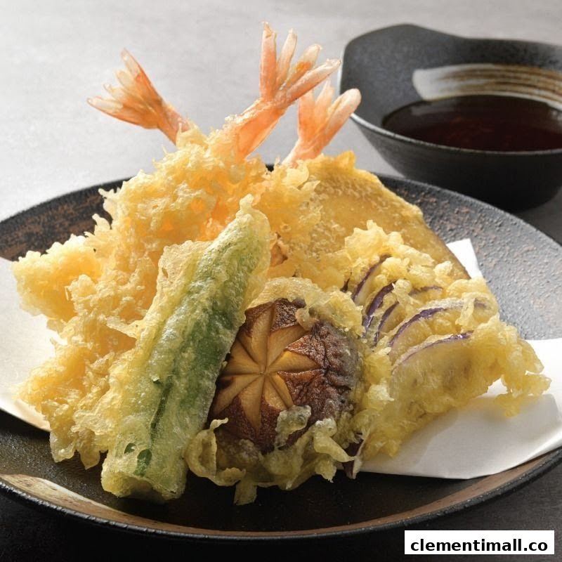 A plate of crispy golden tempura featuring shrimp, mushroom, and various vegetables with a dipping sauce.
