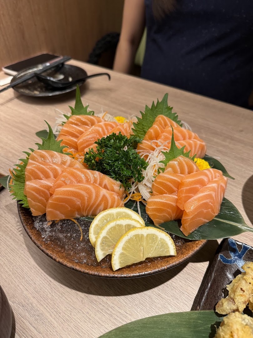 A vibrant plate of fresh salmon sashimi with lemon slices and garnish, served on a wooden table.