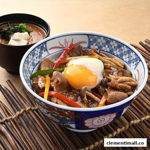 A Japanese donburi bowl featuring meat, mushrooms, vegetables, and a poached egg, served with a side of miso soup.