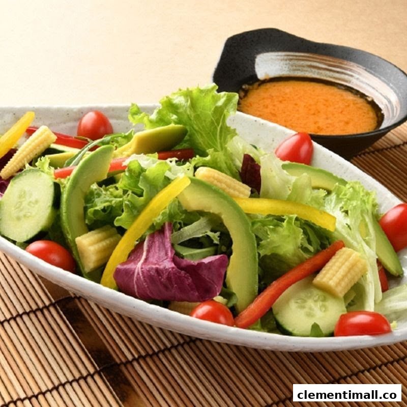 A vibrant fresh salad with avocado, cherry tomatoes, and mixed greens, served with a side of dressing.