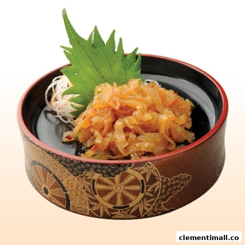 A close-up of a Japanese appetizer, possibly seasoned jellyfish, served in a decorative bowl with a green shiso leaf.