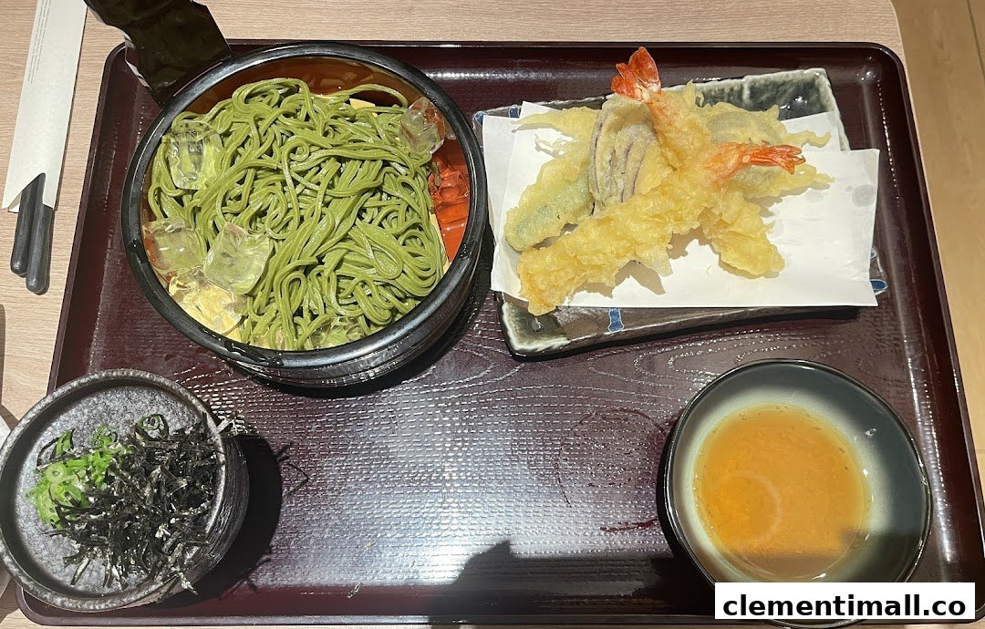 A delicious Japanese meal featuring green tea soba noodles with tempura and dipping sauce.