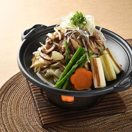 A close-up of a Japanese hot pot dish with mushrooms, vegetables, and meat in a black pot.
