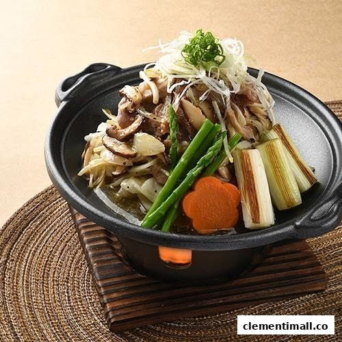 A close-up of a Japanese hot pot dish with mushrooms, vegetables, and meat in a black pot.
