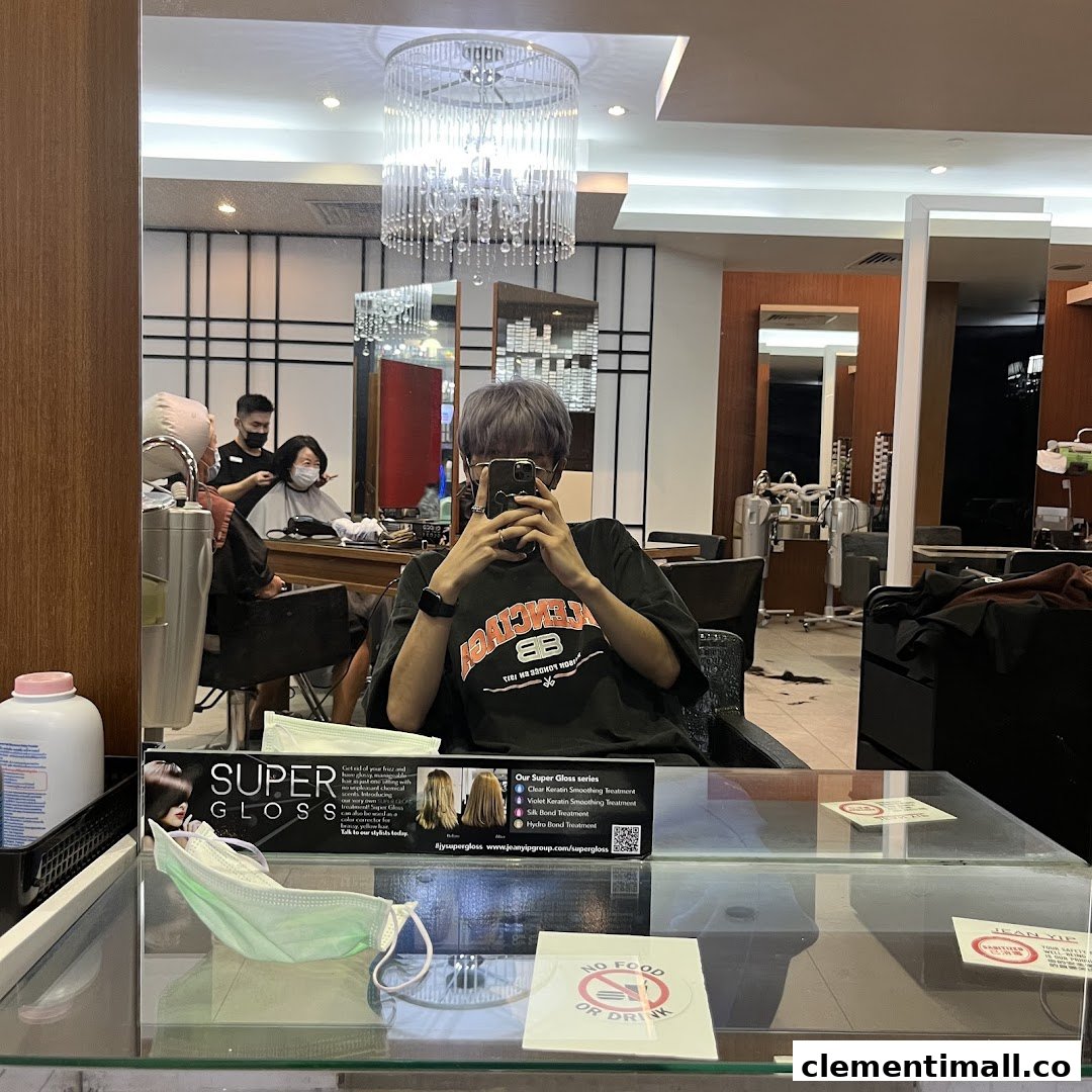 A customer in a hair salon chair, reflected in a mirror, with staff attending to another client.