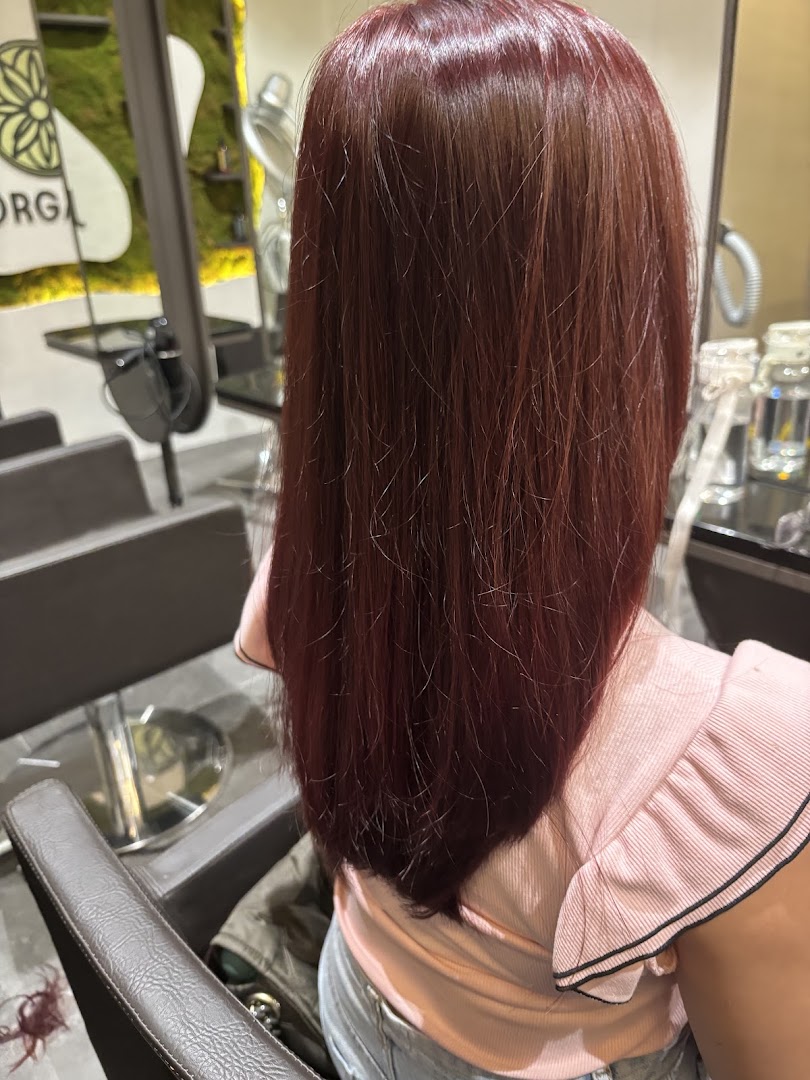 A person with freshly styled, reddish-brown hair sitting in a salon chair.