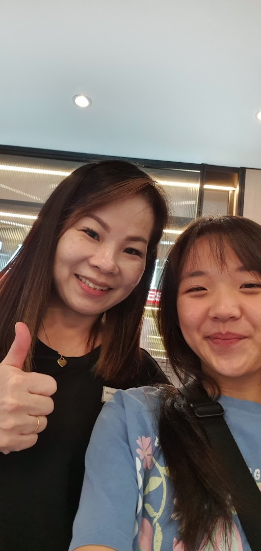 Two smiling individuals, one staff member giving a thumbs-up, inside Jean Yip Hairdressing.