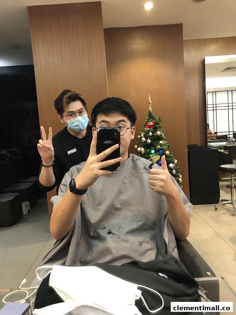A customer takes a selfie with a stylist in a modern salon, featuring a festive Christmas tree.