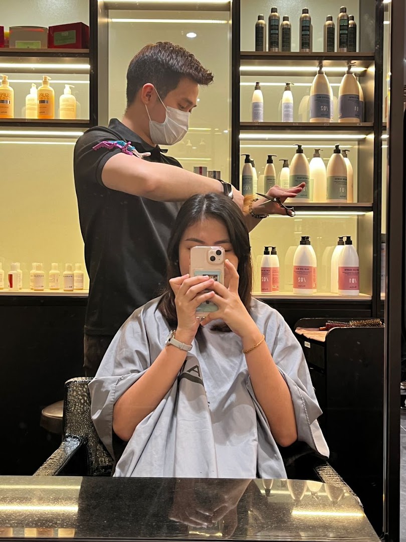 A stylist gives a customer a haircut inside Jean Yip Hairdressing, surrounded by hair products.