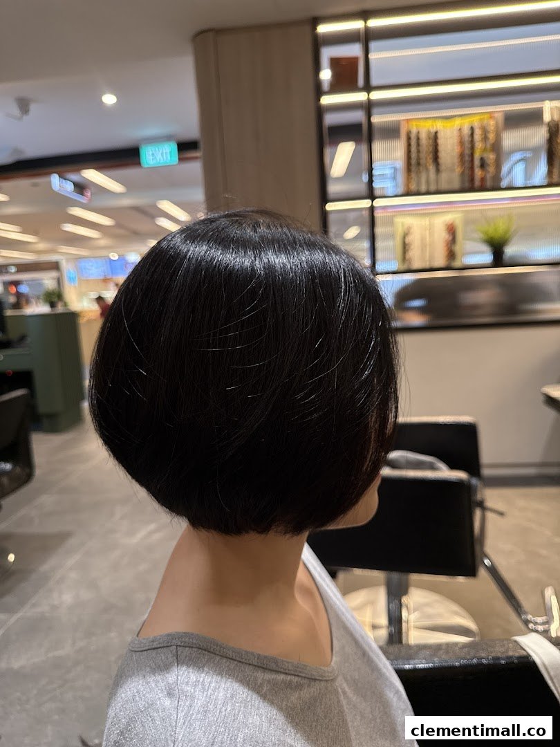 A person showcasing a freshly styled, sleek short bob haircut inside a hair salon.