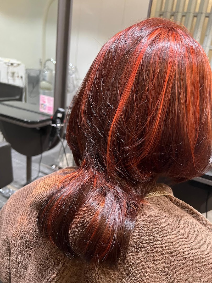 Close-up of a client's hair showcasing vibrant red and orange highlights after a salon treatment.