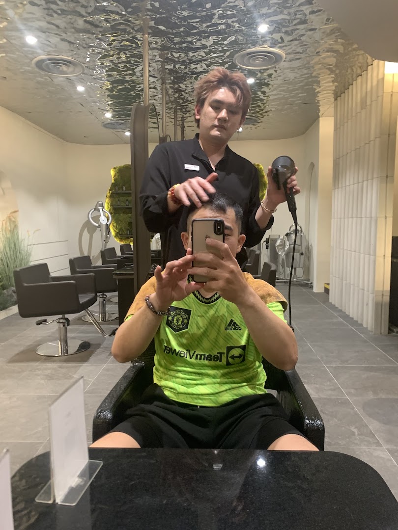 A stylist blow-drying a client's hair in a modern salon setting.
