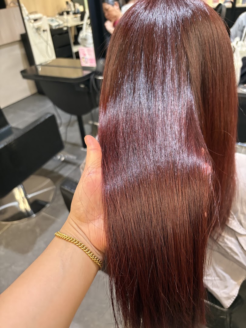 Close-up of vibrant, reddish-brown hair held by a hand, showcasing a fresh salon treatment.