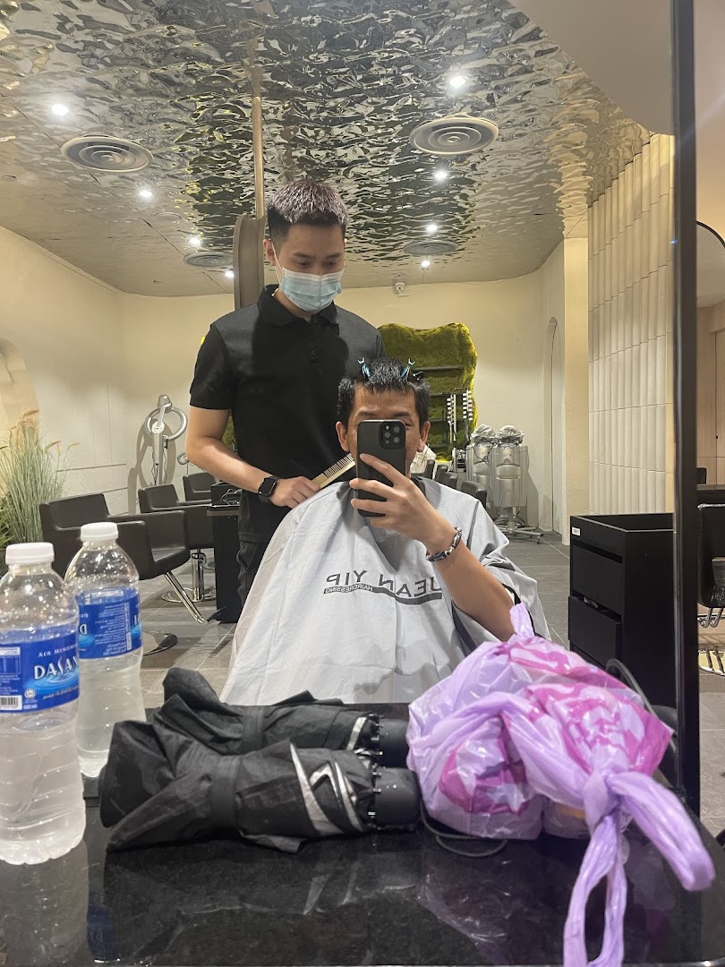 A customer receives a haircut from a stylist inside Jean Yip Hairdressing salon, reflected in a mirror.