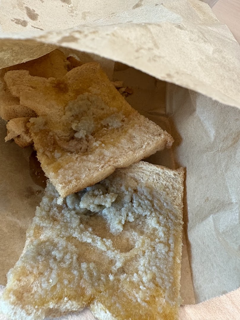 Close-up of kaya toast with a sweet topping, served in a brown paper bag.