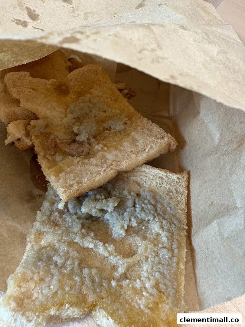 Close-up of kaya toast with a sweet topping, served in a brown paper bag.