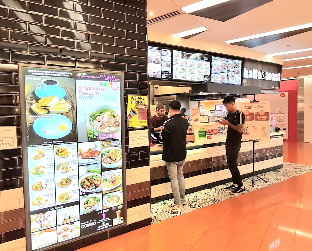 Customers at Kaffe & Toast ordering from a digital menu display featuring various local dishes and drinks.