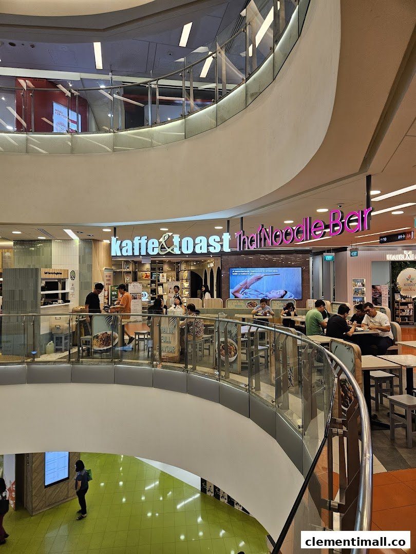 Diners enjoy meals at Kaffe & Toast Thai Noodle Bar within a bustling shopping mall environment.