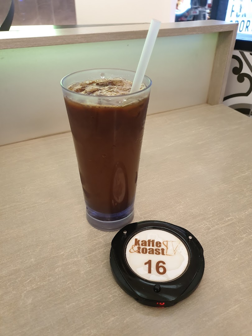 An iced coffee drink and a Kaffe & Toast pager on a light-colored table.