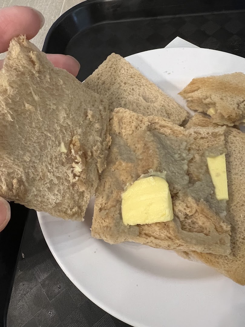 Close-up of several pieces of toast with butter on a white plate, held by a hand.
