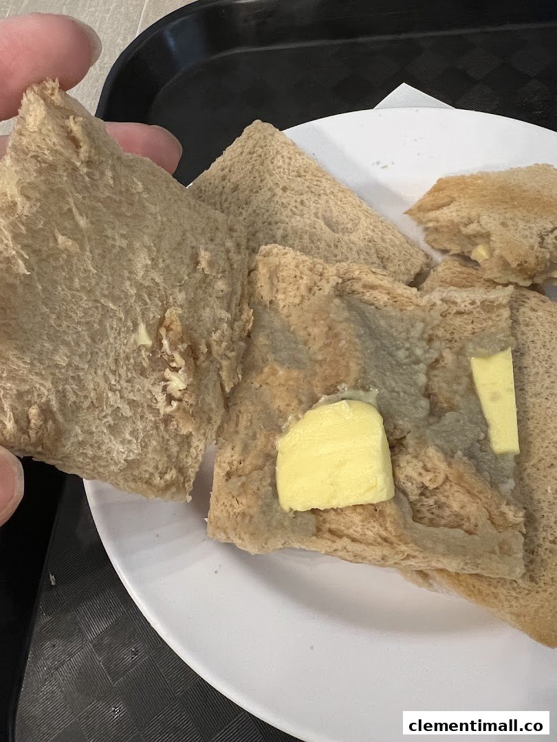 Close-up of several pieces of toast with butter on a white plate, held by a hand.