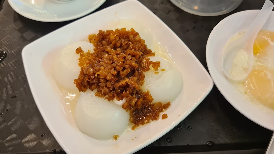 A close-up of traditional Asian breakfast items, including white rice cakes with savory topping and soft-boiled eggs.