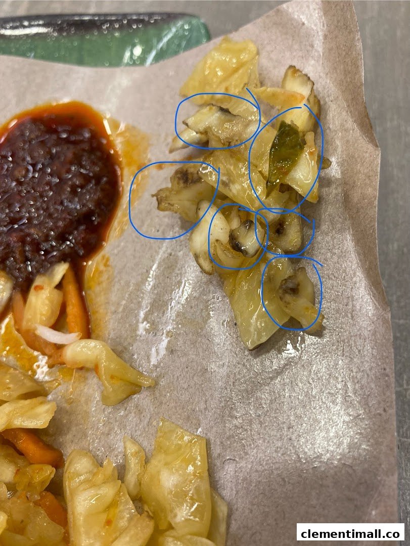 Close-up of a side dish featuring pickled vegetables and a rich sauce, served on paper.